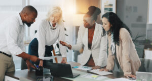 Team members crowded over a table going over reports in the office.
