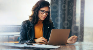 A businesswoman with glasses is focusing on her laptop screen that houses modern trust accounting software.